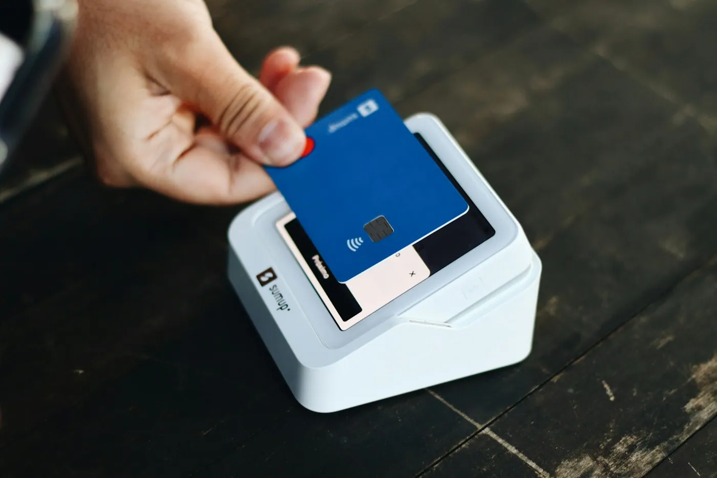 A customer holding a bank card over a contactless payment terminal