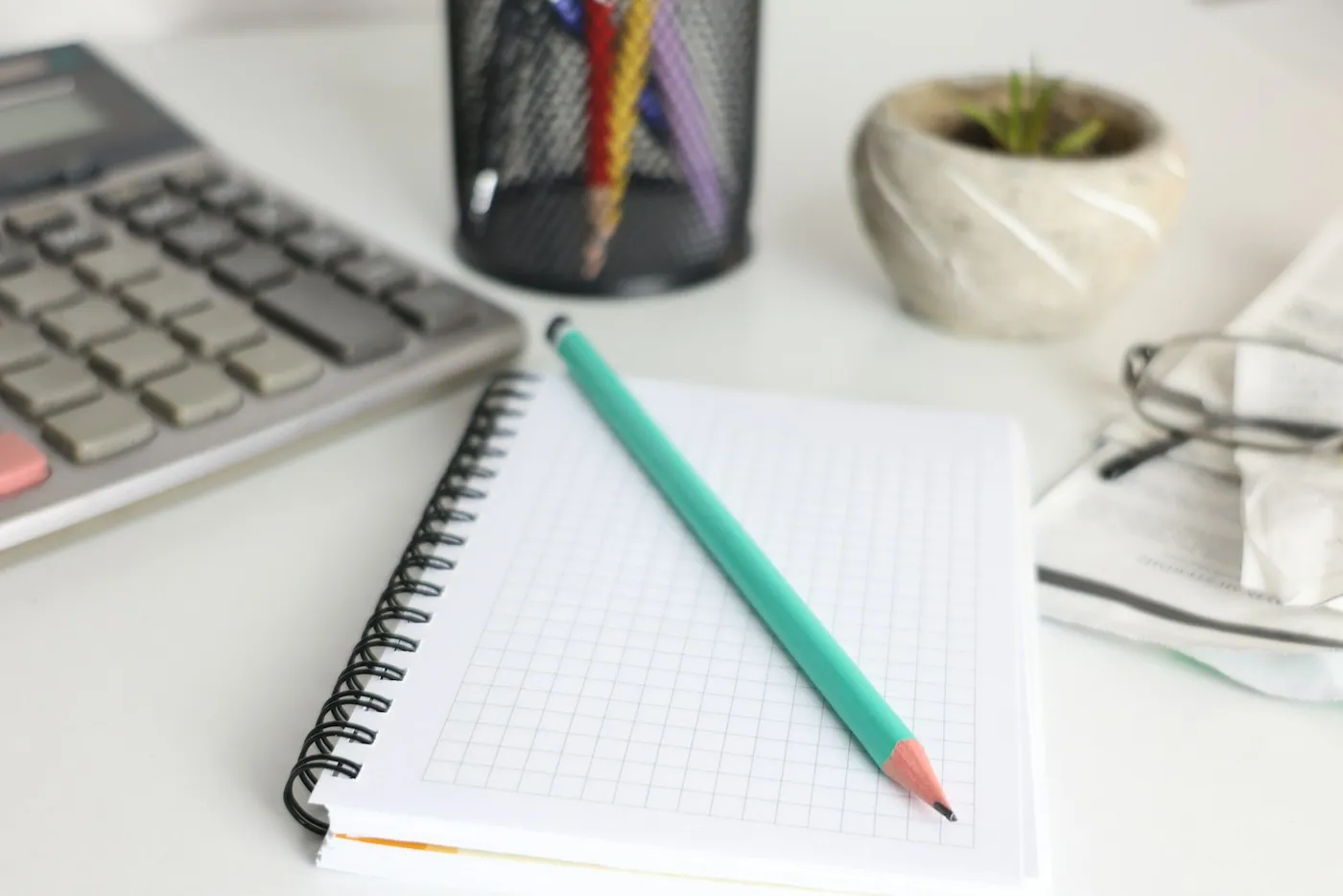 A calculator, graph-paper notebook and a pencil on a working desk