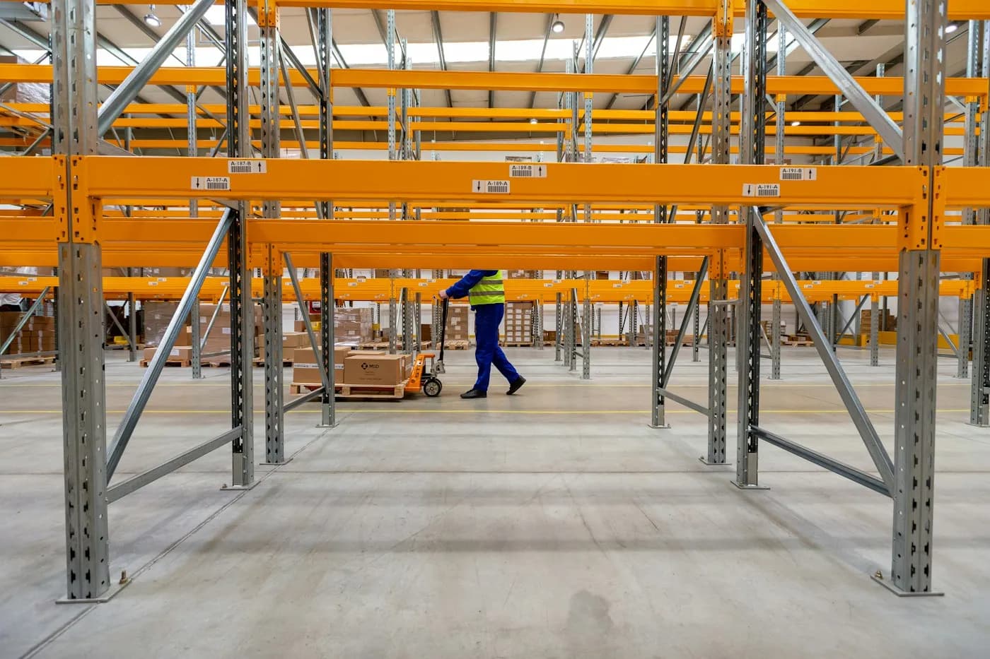 A worker walking between stocked warehouse shelves
